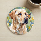 Labrador Retriever Watercolor Butterfly Bloom Drink Coaster cork coaster shown on a warm limestone surface beside a mug