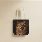 Pomeranian Tote Bag canvas tote bag hanging by its handles against a warm limestone wall
