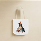 Border Collie Halloween Tote Bag canvas tote bag hanging by its handles against a warm limestone wall